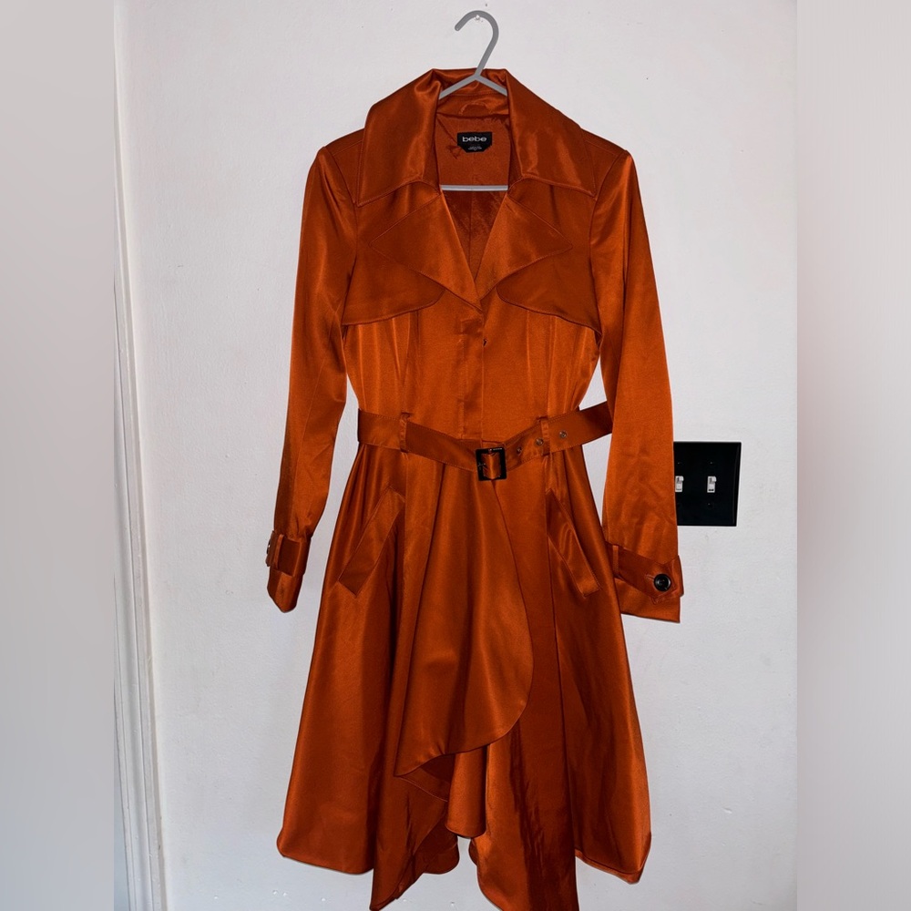 This is a Bebe orange satin-finish trench coat.
